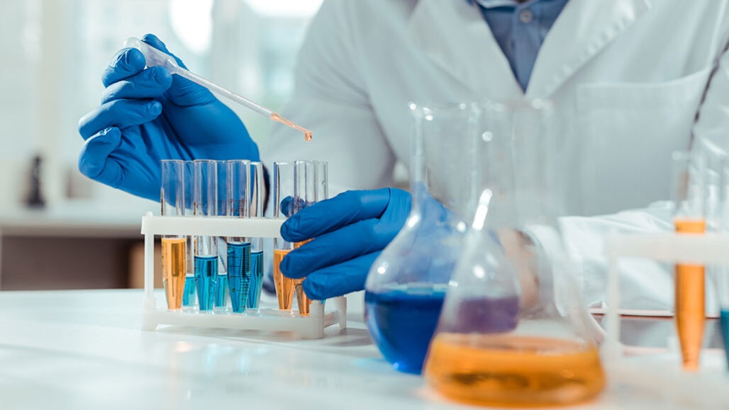 A chemist holding a test tube, representing the discovery of a new substance by the ADJD Lab.